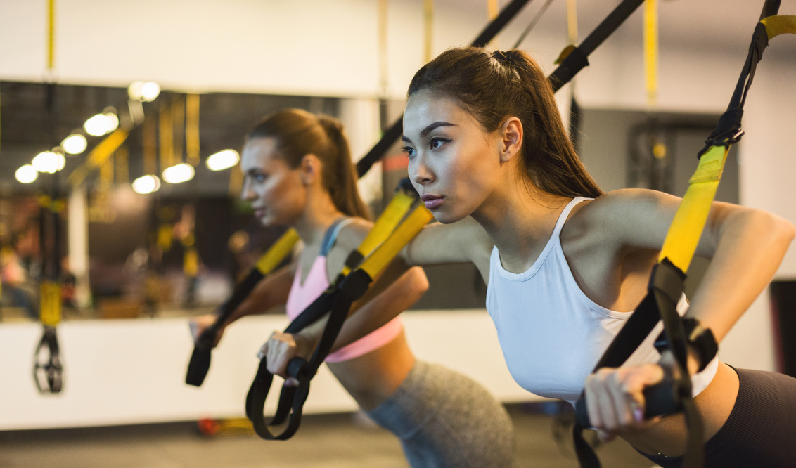 Women training arms with trx fitness straps